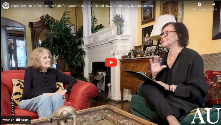 A still from the video of Gloria Steinem's Interview, showing Gloria Steinem sitting in her living room, talking to Carol Jenkins.